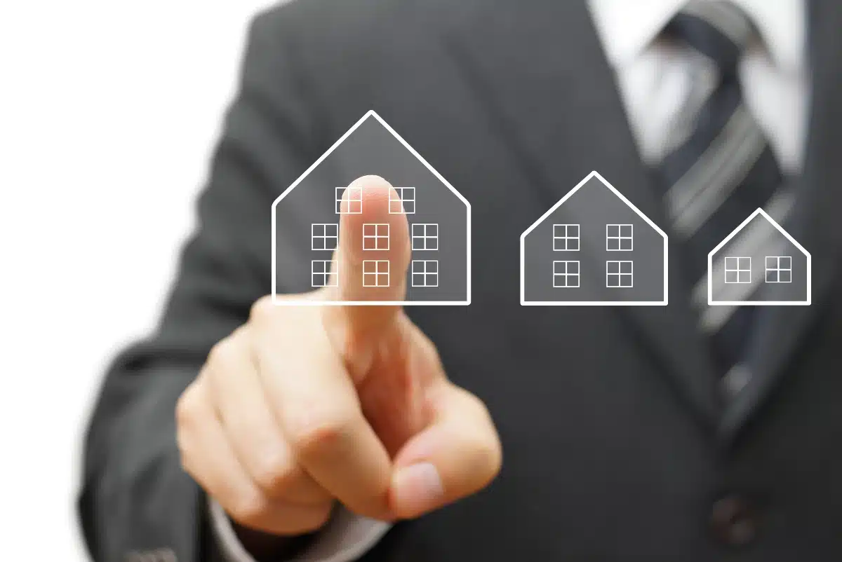 homme qui pointe du doigt une maison digitale, déficit foncier et revente immobilière homme qui pointe du doigt une maison digitale, déficit foncier et revente immobilière