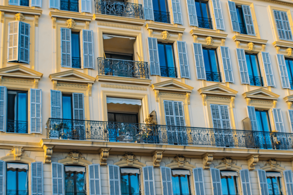 Gros plan sur un immeuble jaune aux volets turquoise, plein cadre, Nice,
